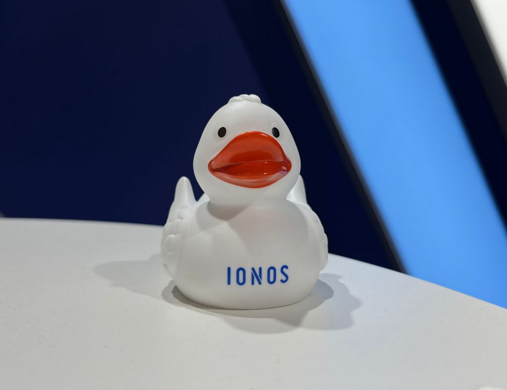 Weiße Gummi-Ente mit blauem IONOS Logo Aufdruck