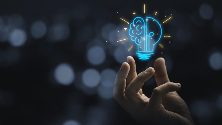 Eine realistische Hand hält eine leuchtende, stilisierte Glühbirne mit einem Gehirn-Icon, um die transformativen KI-Trends für Domains 2026 zu visualisieren.