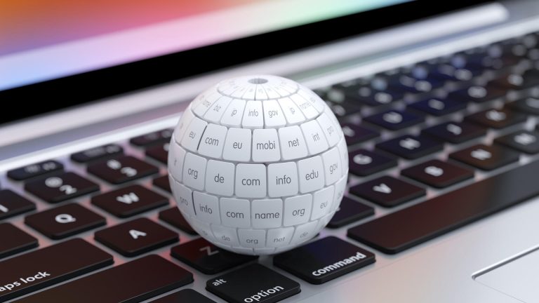 Eine detaillierte Nahaufnahme einer weißen Kugel, übersät mit unterschiedlichen TLD-Endungen, die auf einer Laptop-Tastatur ruht. Die Abbildung symbolisiert die Marktentwicklung neuer gTLDs, gestützt auf Daten des Global Domain Reports 2026.